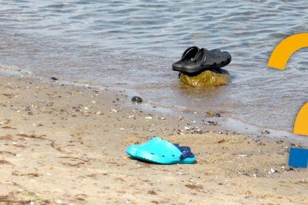 Schuhe im Wasser am Strand mit Fragezeichen
