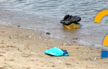 Schuhe im Wasser am Strand mit Fragezeichen